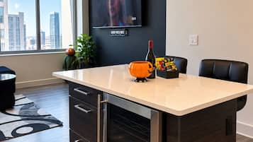 A modern kitchen with a large island, a built-in oven, and a flat-screen TV mounted on the wall.
