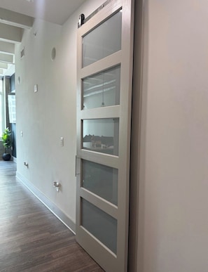 A hallway with a sliding glass door, a potted plant, and a light switch on the wall.