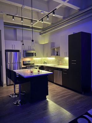 A modern kitchen with stainless steel appliances, a central island, and pendant lighting.