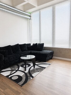 A modern living room with a sectional sofa, a coffee table, and a patterned rug.