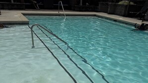 A swimming pool with clear water, a metal ladder, and a tiled edge. - The Midnight Luxury Condo With Pool, Gym & Minutes to Downtown ATL (Atlanta)
