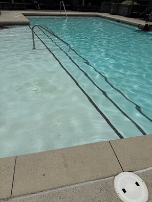 A swimming pool with clear water, a metal ladder, and a tiled edge. - The Midnight Luxury Condo With Pool, Gym & Minutes to Downtown ATL (Atlanta)