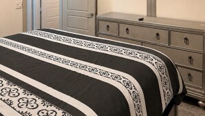 A bedroom with a bed, dresser, TV, and an open door leading to another room. - The Midnight Luxury Condo With Pool, Gym & Minutes to Downtown ATL (Atlanta)