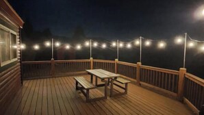 Puinen terassi, jossa on valoketju, pöytä ja penkkejä.