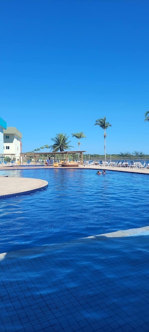 A swimming pool with lounge chairs and palm trees in the background. - Paradise between the sea and the lagoon! Premium condominium in Arraial do Cabo, Rio de Janeiro. (Arraial do Cabo)