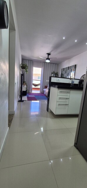 A modern kitchen with a central island, a dining area with a purple rug, and a view of a balcony. - Paradise between the sea and the lagoon! Premium condominium in Arraial do Cabo, Rio de Janeiro. (Arraial do Cabo)
