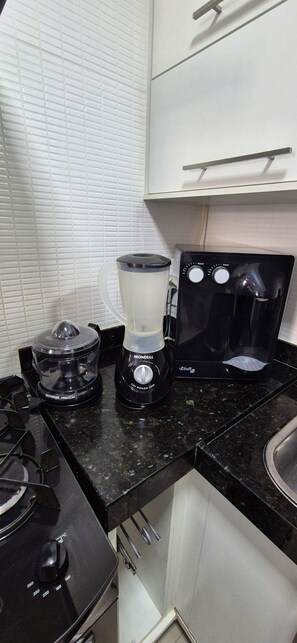 Een keuken met een fornuis, een blender en een koffiezetapparaat.