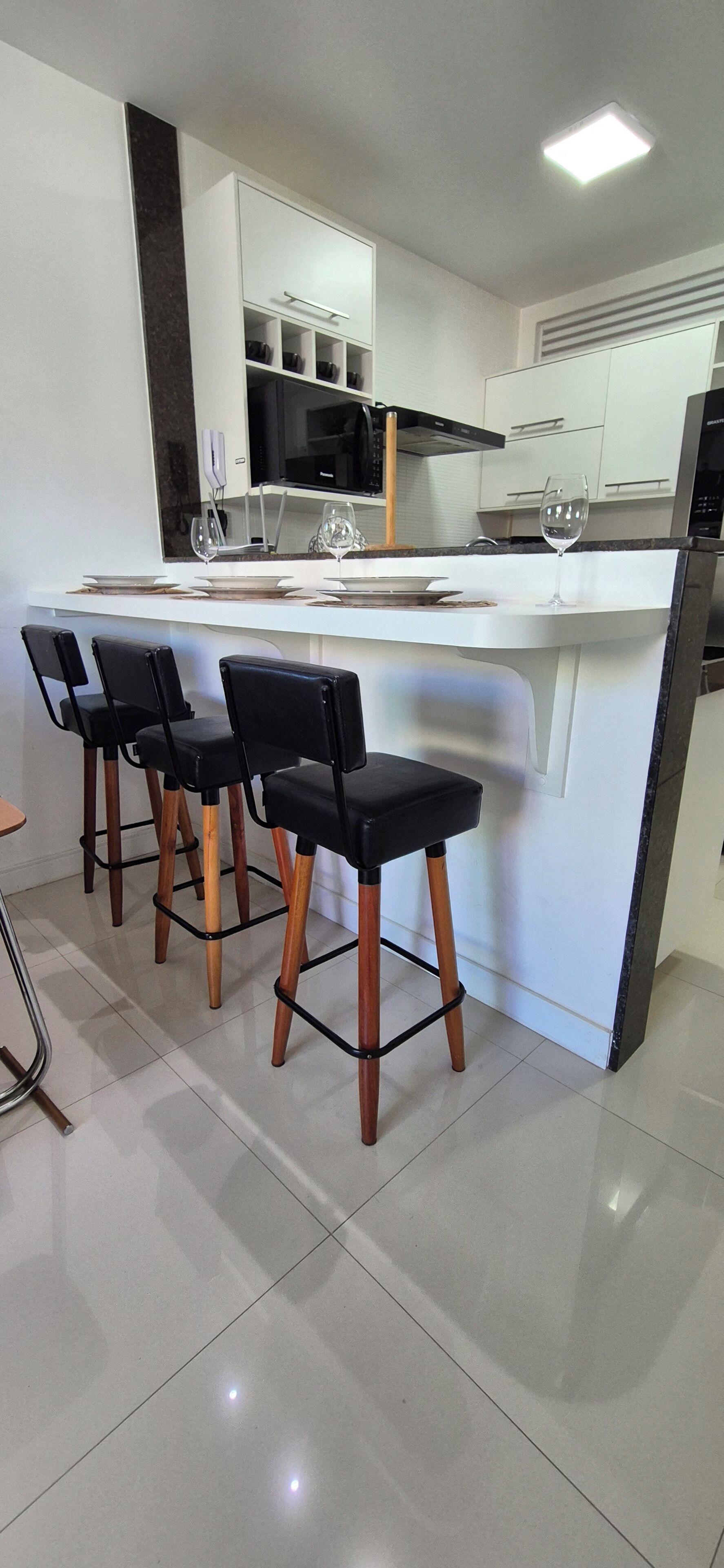 A modern kitchen with a central island, bar stools, and a refrigerator.