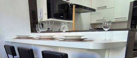 A modern kitchen with a central island, bar stools, and a refrigerator.