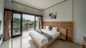A spacious bedroom with a large bed, a wooden headboard, and a balcony with a view of the surrounding area. - Villa Catur Seminyak (Badung)