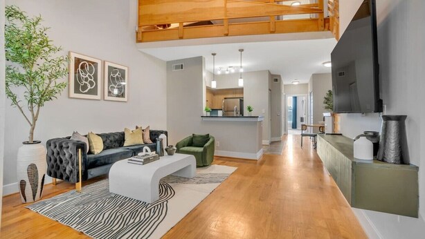 A modern living room with a sofa, coffee table, and a TV. There is a kitchen in the background. - Cozy retreat minutes away from FIFA World Cup (Atlanta)