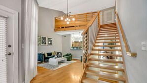 A modern interior with a wooden staircase, a living area with a sofa and coffee table, and a kitchen in the background. - Cozy retreat minutes away from FIFA World Cup (Atlanta)