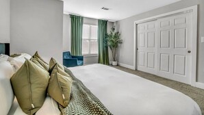 A bedroom with a large bed, a blue chair, a potted plant, and a white door. - Cozy retreat minutes away from FIFA World Cup (Atlanta)