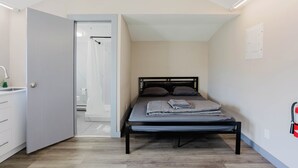 Un dormitorio con cama, ducha y puerta que da al baño.