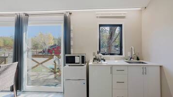 Cocina compacta con microondas, refrigerador, pileta y ventana con vista a una terraza.