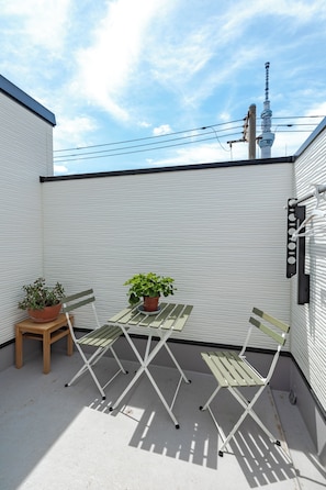 A small outdoor space with a table and two chairs, a potted plant, and a view of a tower in the background. - Located 650 meters from Tokyo Skytree, with direct access from Narita and Haneda Airports. A two-story single-family home that accommodates up to 7 guests. A 4-minute walk from the nearest station. (墨田区)