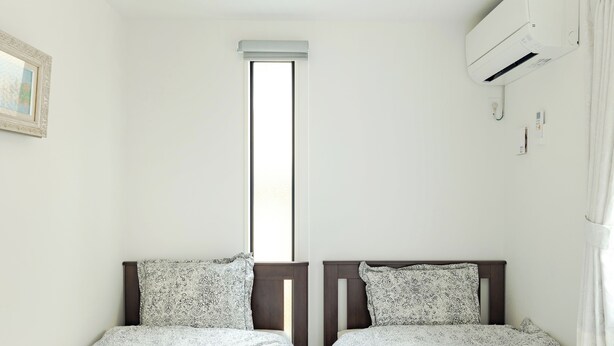 A room with two beds, a window, an air conditioning unit, and a framed picture on the wall. - Located 650 meters from Tokyo Skytree, with direct access from Narita and Haneda Airports. A two-story single-family home that accommodates up to 7 guests. A 4-minute walk from the nearest station. (墨田区)