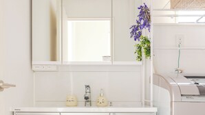 A modern kitchen with white cabinetry, a built-in oven, and a large mirror above the countertop. - Located 650 meters from Tokyo Skytree, with direct access from Narita and Haneda Airports. A two-story single-family home that accommodates up to 7 guests. A 4-minute walk from the nearest station. (墨田区)
