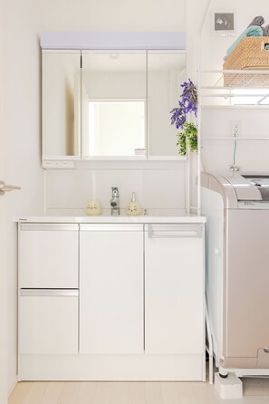 A modern kitchen with white cabinetry, a built-in oven, and a large mirror above the countertop. - Located 650 meters from Tokyo Skytree, with direct access from Narita and Haneda Airports. A two-story single-family home that accommodates up to 7 guests. A 4-minute walk from the nearest station. (墨田区)