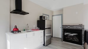 Una cocina moderna con un refrigerador de acero inoxidable, un microondas, una tetera y una chimenea.