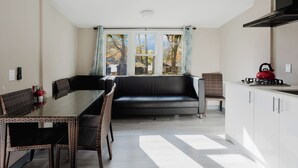 Una cocina moderna con comedor, sofá y vistas amplias por ventanas grandes.