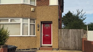 Een twee verdiepingen tellend huis met een rode voordeur, een bakstenen gevel en een betegelde oprit.