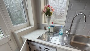 Een praktische keuken met een ingebouwde wasmachine, een spoelbak en een raam met decoratief glas.