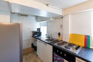 Eine kleine Küche mit Kühlschrank, Mikrowelle, Spüle und Herd.