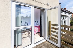 Ein Zimmer mit einer großen Schiebeglasdoor, die zu einem Außenbereich mit einer Holzterrasse führt.