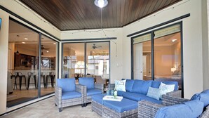 An outdoor patio with wicker furniture, a ceiling fan, and a view into the house. - Pool Waterfall | 4BR | S. Exposure | Dogs OK (Cape Coral)