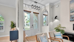 A living room with a fireplace, two armchairs, a coffee table, and a door leading to an outdoor area. - Pool Waterfall | 4BR | S. Exposure | Dogs OK (Cape Coral)
