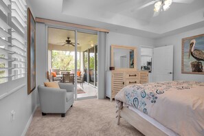 A bedroom with a bed, a dresser, a chair, a desk, and a sliding glass door leading to a balcony. - Golf & Beach Shuttle | Estero | 30 Days (Estero)