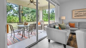 Ein modernes Wohnzimmer mit Sofa, Sesseln, Esstisch und einem Balkon mit Glastüren.