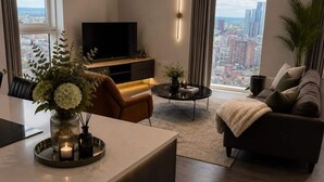 Ein modernes Wohnzimmer mit Flachbildfernseher, einer Couch, einem Couchtisch und einem Essbereich mit einer Blumenvase.