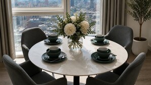 Ein runder Tisch mit vier Stühlen, eine Vase mit weißen Blumen und zwei Tee-Sets mit Untertassen.