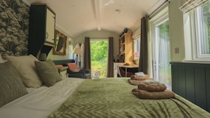 A bedroom with a bed, a desk, and a view of the outdoors.
