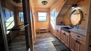 Een houten chalet binnen met een keuken, een bank en een raam met uitzicht.