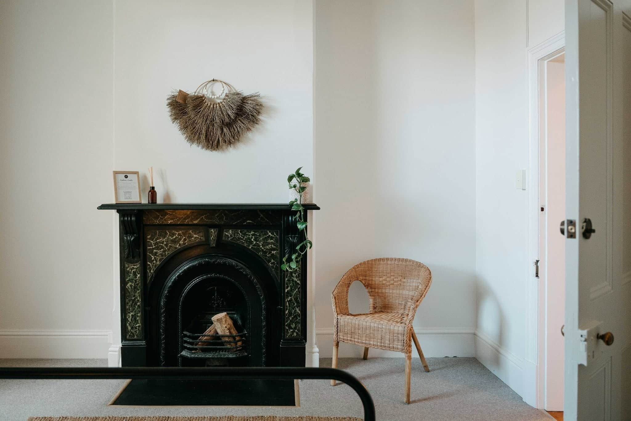 A room with a fireplace, a wicker chair, and a door.
