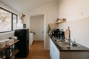 Eine Küche mit Kühlschrank, Mikrowelle, Spüle und Holzregalen.