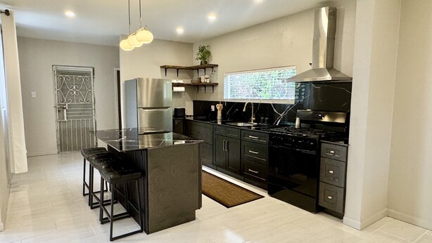 A modern kitchen with a central island, stainless steel appliances, and a large window. - Private 3 Bedroom Tropical Luxury Villa · St. Kitts (Basseterre)