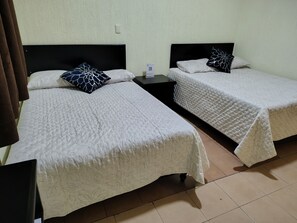 Two beds with floral-patterned bedding, a nightstand between them, and a light switch on the wall. - Hotel Casa Real Xilotepec  (Jilotepec)