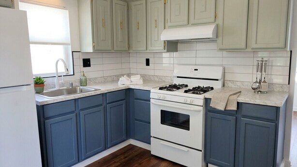A kitchen with blue cabinets, a white stove, and a sink. - Lovely 2-bedroom house with AC near charming Delaware Bay (Lower Township)