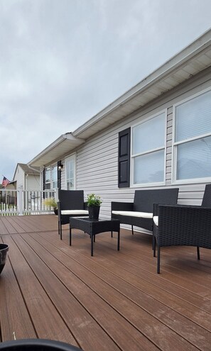 Eine überdachte Terrasse mit Sitzgelegenheit, darunter ein Tisch und zwei Stühle.