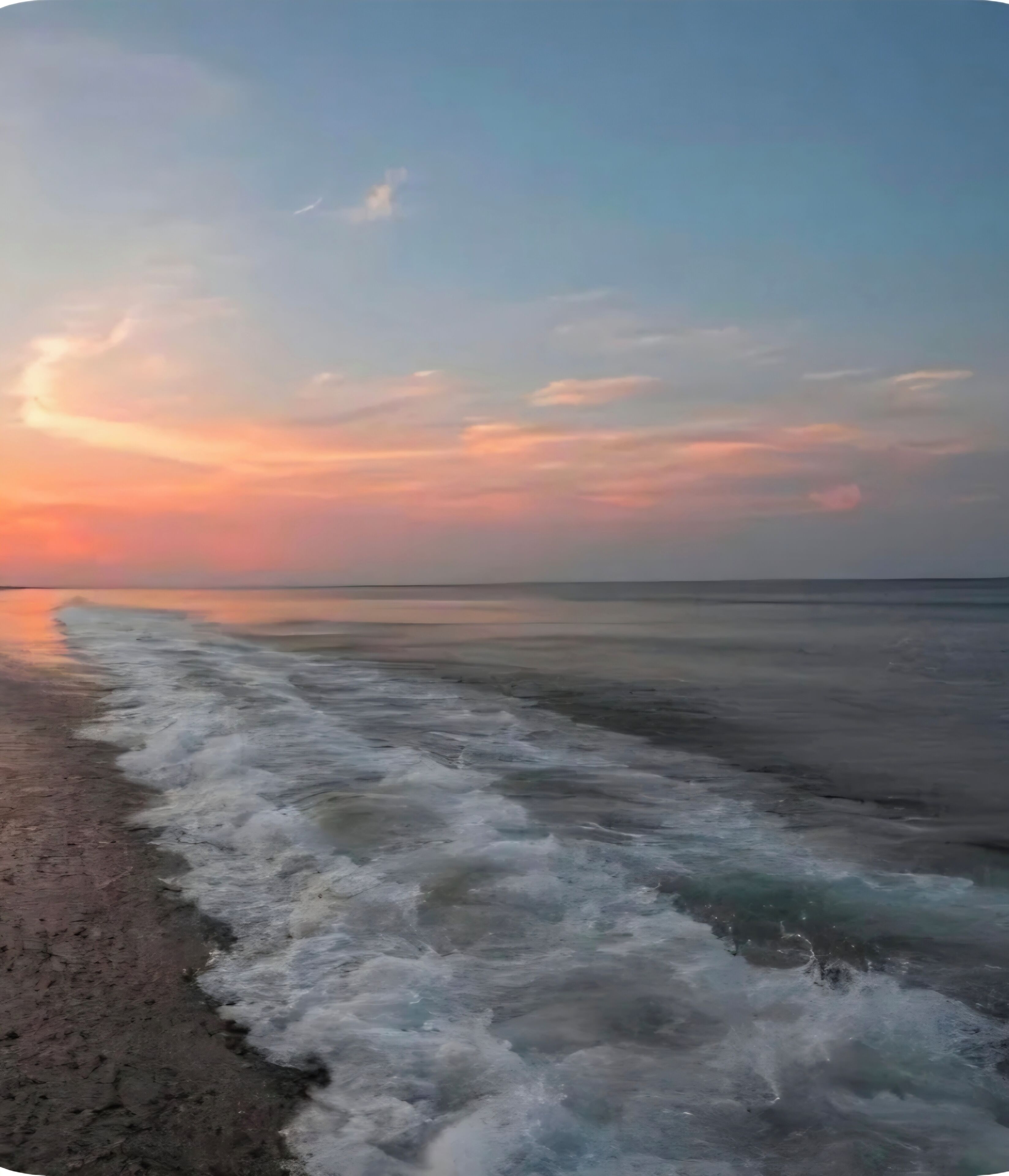 A beach with waves at the shore and a clear sky.