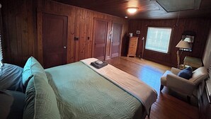 A room with a bed, a chair, a dresser, and a window with blinds.