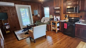 A wooden-paneled room with a kitchen area including a stove, microwave, and refrigerator.
