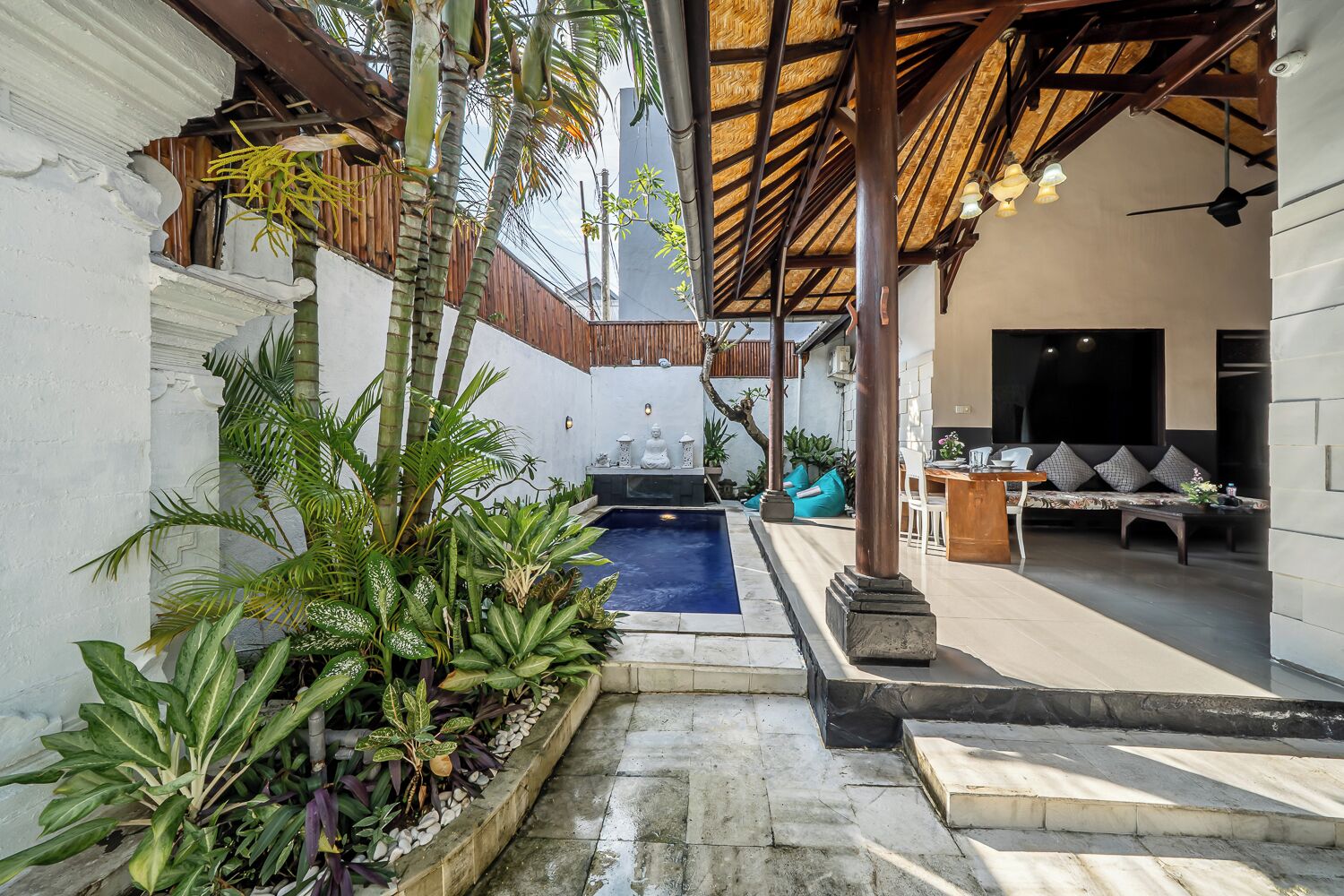 Un'area piscina con idromassaggio, posti a sedere e piante tropicali.