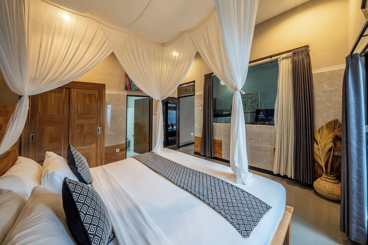 A bedroom with a bed, curtains, and a view of the outside.