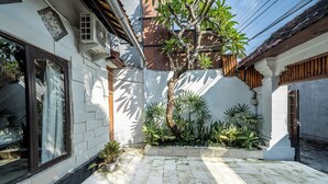 Un cortile con pavimento piastrellato, piante in vaso e un albero.