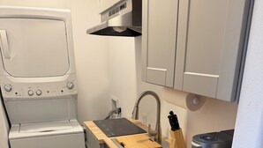 A compact kitchen with a built-in washer and dryer, a wooden countertop, a sink, and a coffee machine. - Lovely 2-bedroom apartment in Sterling perfect for your getaway (Sterling)